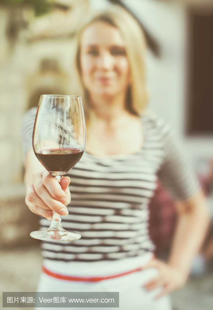 一個女人在室外遞上一杯紅酒。復古的效果。